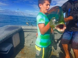kid tries to hold his catch of dorado while fishing in panama