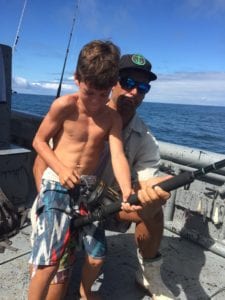 young angler with dads help fishing tuna coast