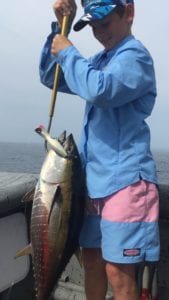 young guest gaffing fish on panama fishing vacation